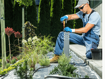 an expert electrician with the full safety and tools fitting lights in the garden.