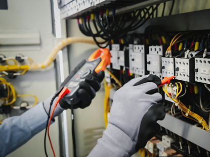 Electrician with grey gloves with cramp meter to test electrical wiring