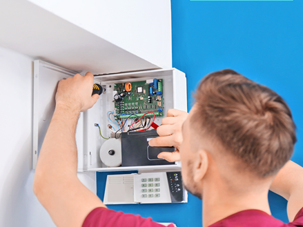 an electrician is fitting the alarm in the security box.
